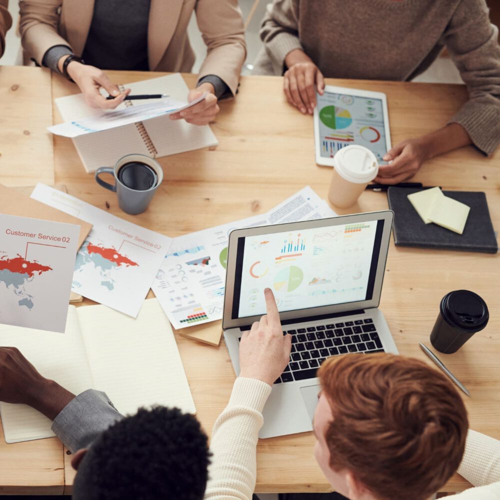 Vier Personen sitzen arbeitend an einem Schreibtisch.