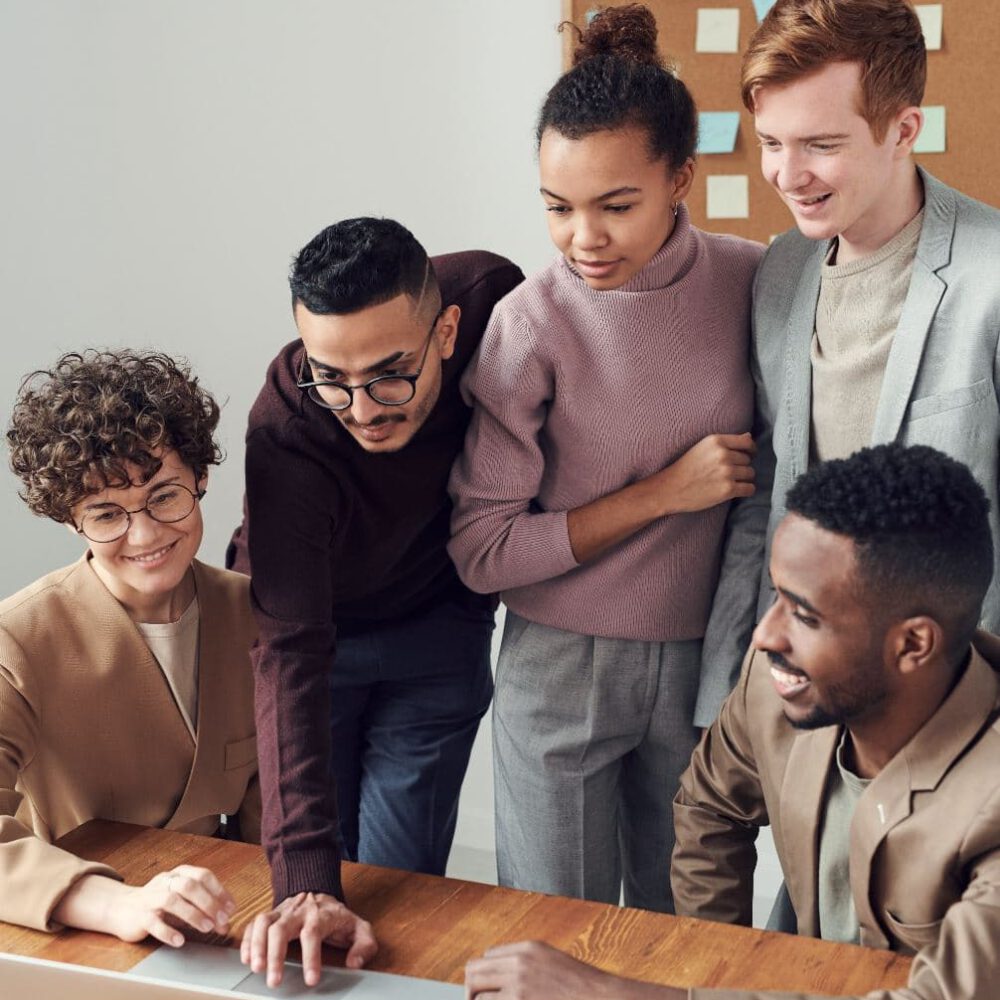 Vier Personen blicken auf einen Computerbildschirm