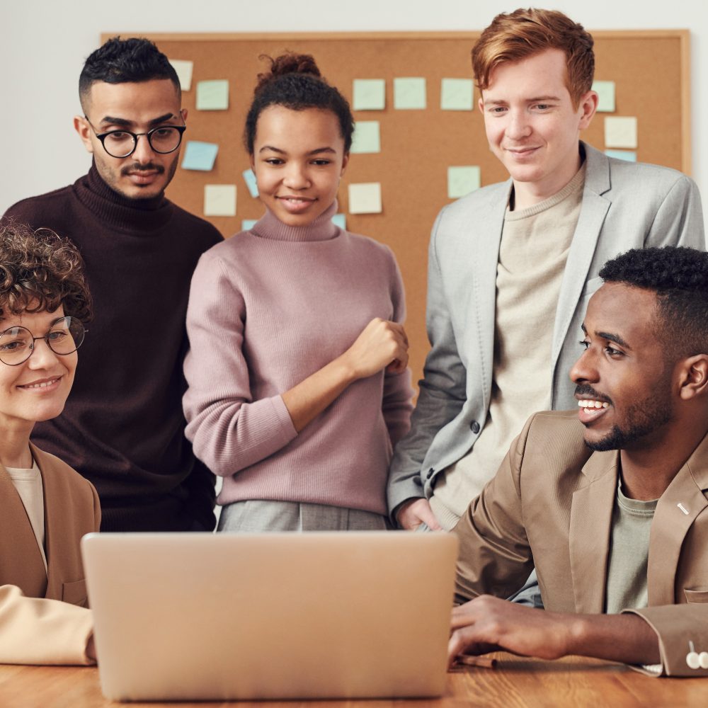 Fünf Menschen stehen vor einem Laptop und beratschlagen sich